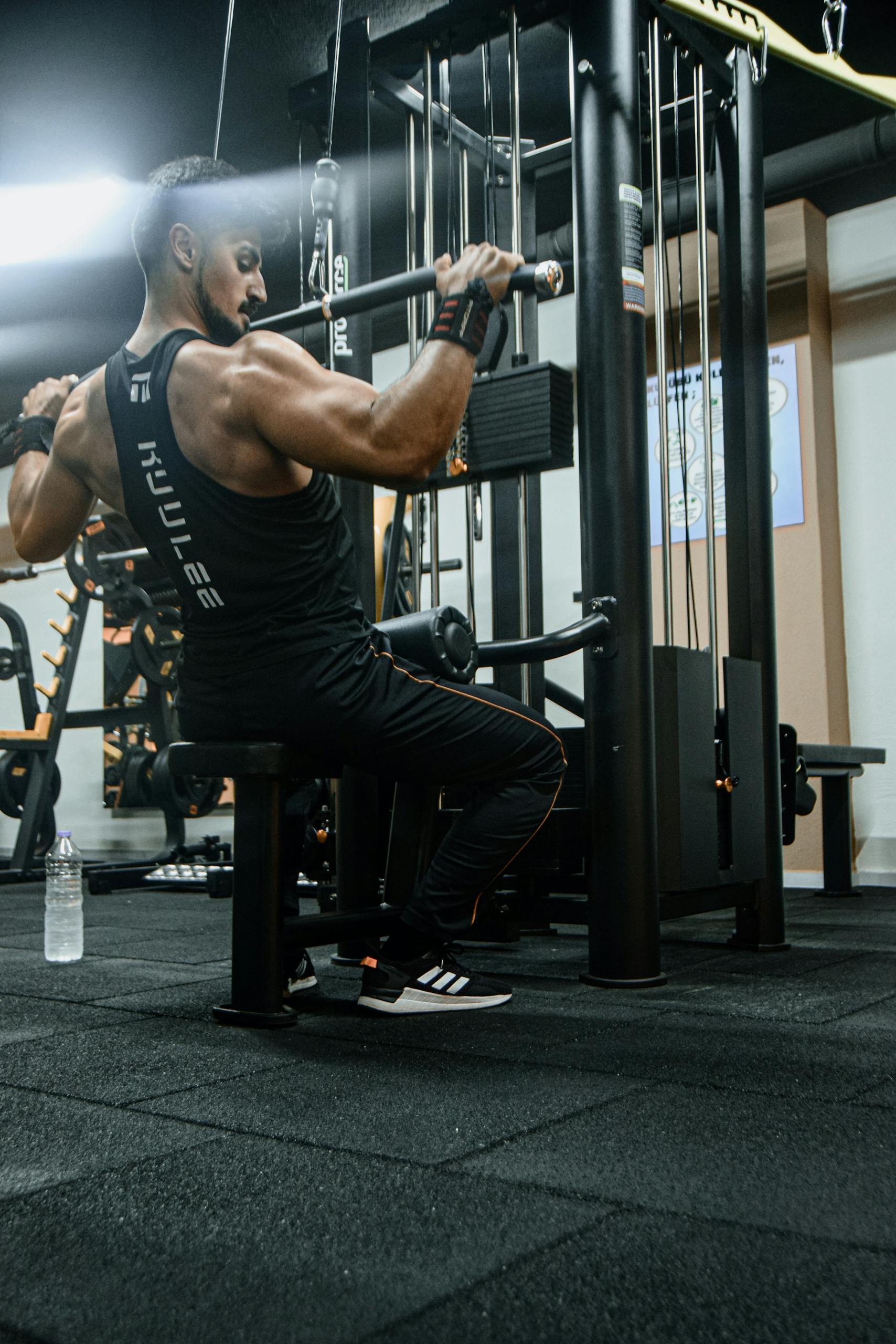 A Muscular Man using a Lat Pull-Down Machine in a Gym